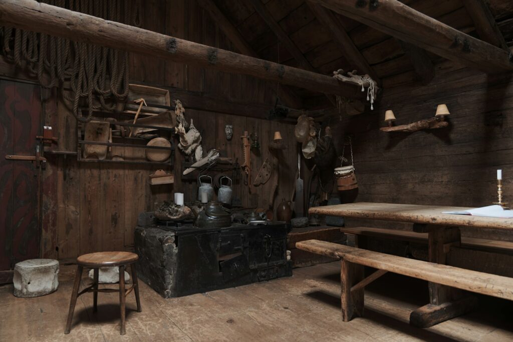 Grande table de bois et bancs dans une salle ancienne aux murs de rondins, éclairée à la bougie